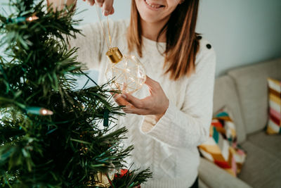 Midsection of woman holding christmas tree at home