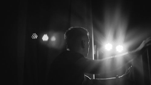 Man standing by illuminated lights at music concert