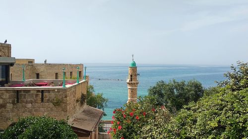 Scenic view of sea and buildings against clear sky