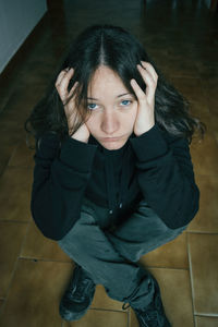 Full length of tensed woman sitting on floor at home