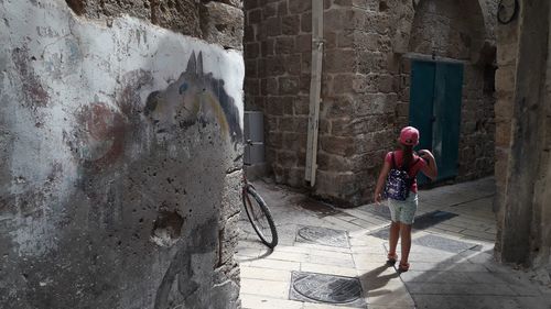 Rear view of woman standing by building