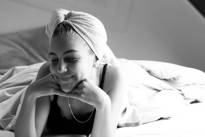 Portrait of young woman lying on bed at home