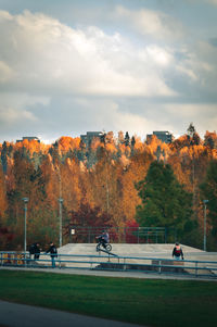People in park during autumn against sky