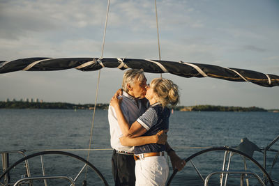 Senior couple lip kissing in boat against sea and sky on sunny day