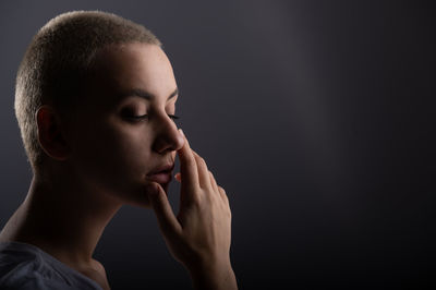 Close-up portrait of young woman against black background