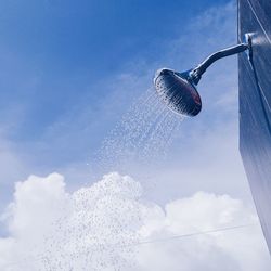 Low angle view of water falling from shower head against sky