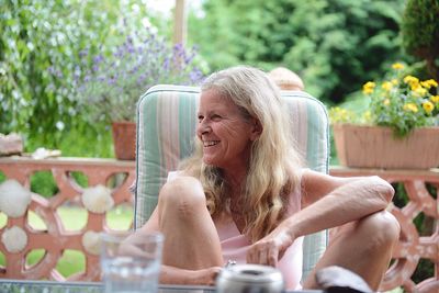 Midsection of woman sitting on seat in yard