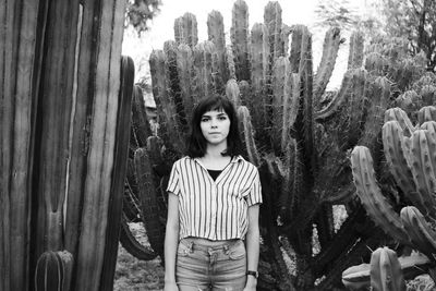 Portrait of beautiful young woman standing against trees