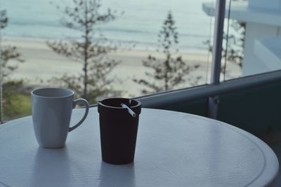 Close-up of coffee cup and ashtray on table