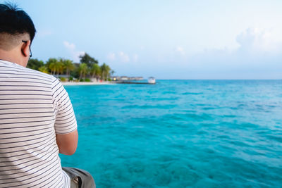 Rear view of man looking at sea against sky