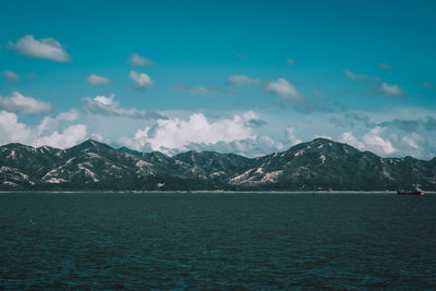 Scenic view of sea by mountains against sky