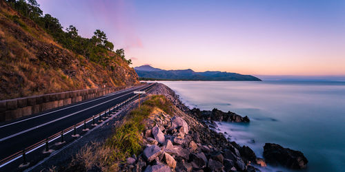 Panoramic view of road by sea against sky during sunset