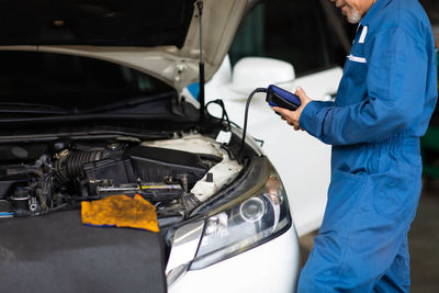 Man checking battery voltage of car at garage