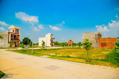 Street by buildings against blue sky