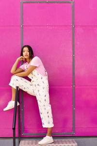 Full length of woman sitting on chair against wall