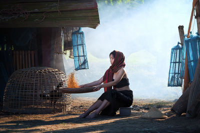 Full length of young woman cleaning food while sitting on field