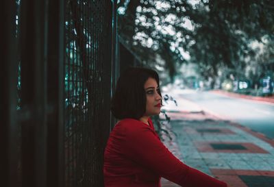 Portrait of young woman looking away while standing on tree