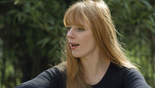 Close-up of young woman looking away against plants