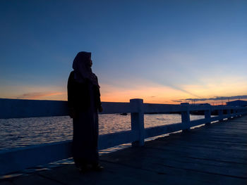 Silhouette of pier over sea against sky during sunset