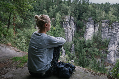 Woman sitting on mountain in forest