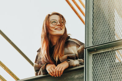 Portrait of young woman standing against window