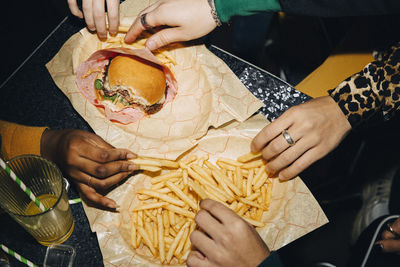 High angle view of friends eating burger and french fries at table in cafe