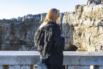 Rear view of woman standing on snow against sky