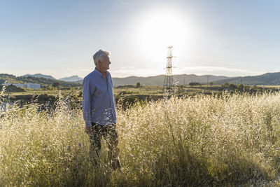 Senior man standing on a field at sunset