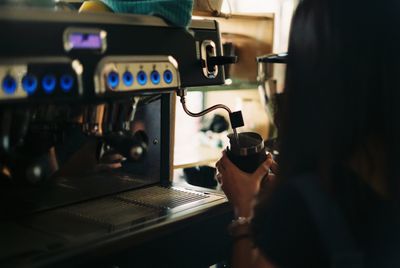 Midsection of man filling cup with coffee in shop