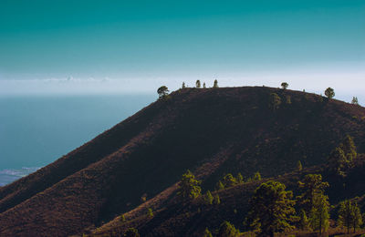 People on mountain by sea against sky