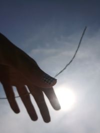Close-up of hand against sky