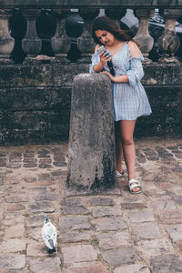 Full length of woman standing against brick wall