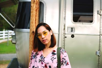 Portrait of beautiful woman against car