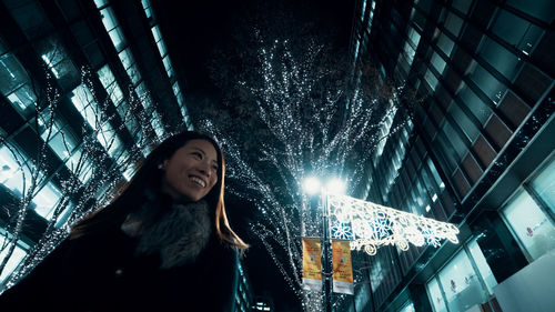 Young woman standing against illuminated building at night