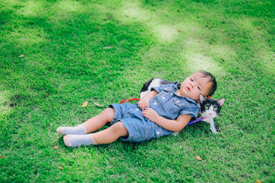 Full length of boy lying down with cat at park