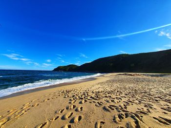 Scenic view of beach against blue sky