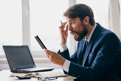 Young man using laptop while sitting on table