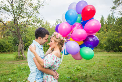 Rear view of couple holding balloons