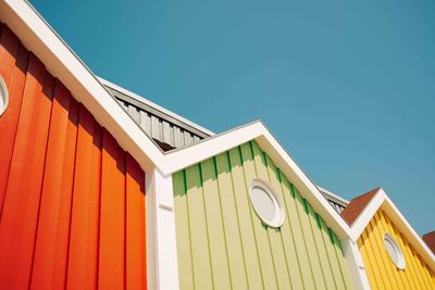 Low angle view of colored wooden building against clear blue sky