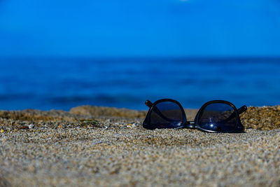 Close-up of empty deck chairs on sand at beach against blue sky