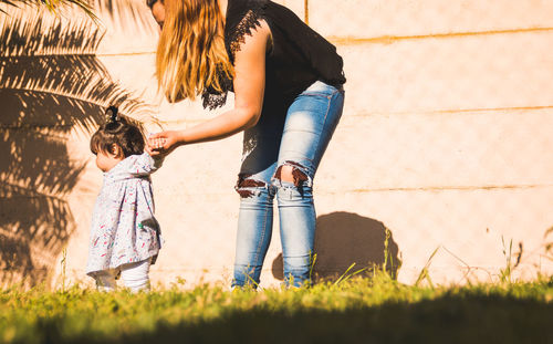 Full length of mother and daughter walking on grass