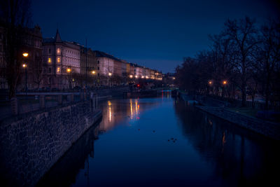 Canal amidst illuminated buildings in city at night