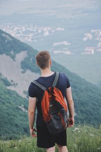 Rear view of man with backpack standing on mountain