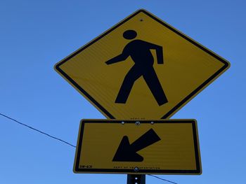 Low angle view of pedestrian crossing road sign against clear blue sky in mount vernon new york 