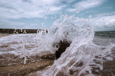 Waves splashing on shore against sky