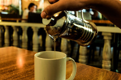 Close-up of hand pouring coffee in cup