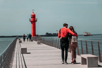 Rear view of people on pier over sea against sky