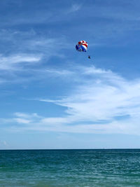 Person paragliding in sea against sky