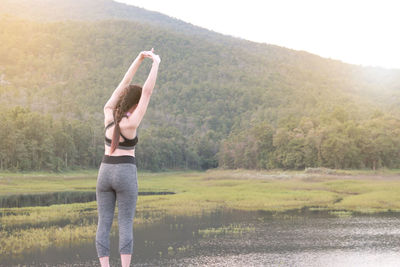 Rear view of woman exercising by lake