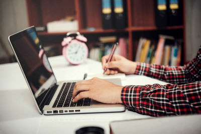 Young woman using laptop on table at home